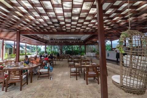 This image shows an outdoor dining area under a wooden pergola structure