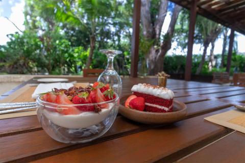 The image shows an outdoor dining setup with a view of lush greenery