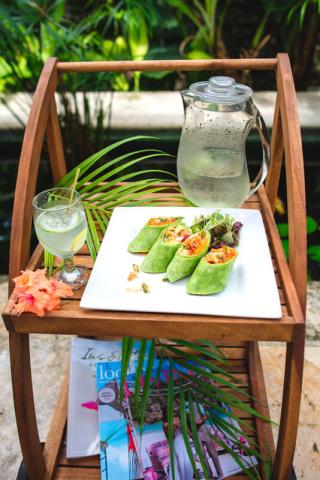 This image features a wooden tray holding a variety of items, set against a lush green background, likely outdoors