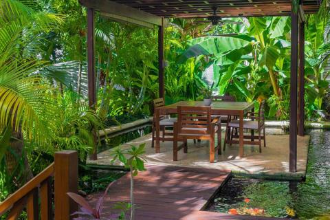 This image shows a serene outdoor dining area nestled in a lush garden
