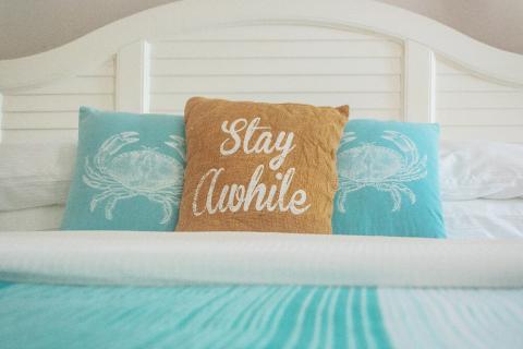 The image shows a neatly made bed with a white headboard and crisp white linens