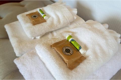 The image shows two neatly folded white towels, possibly in a hotel or a spa setting