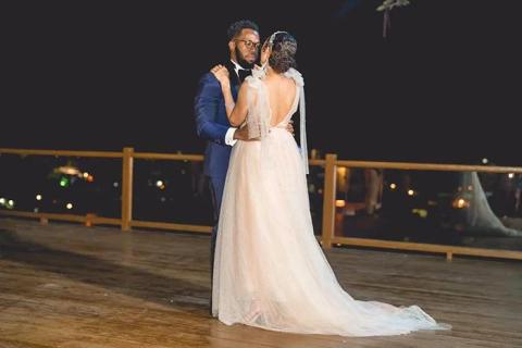 The image depicts a couple sharing a romantic moment on a dance floor, likely during a wedding reception