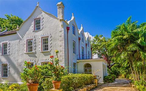 The image shows a charming white house with a distinctive architectural style featuring peaked rooflines and perhaps gothic or Victorian elements