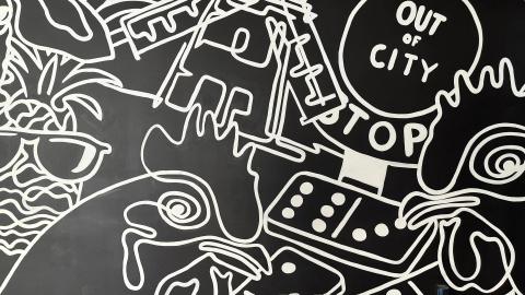 The image displays an abstract, black-and-white graffiti-style mural featuring various shapes and forms outlined in white on a black background