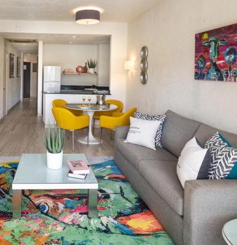 This image features a modern living room design that opens into a kitchen and dining area