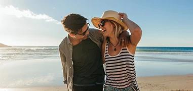 The image shows a happy couple walking on a beach