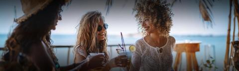 This image depicts three women enjoying a social gathering at a beachfront location