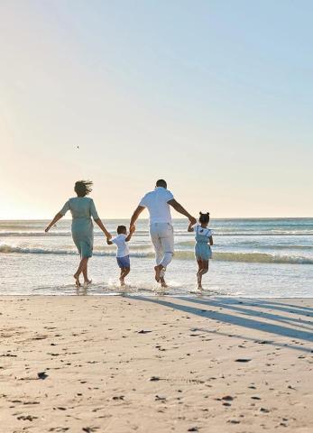 This image captures a heartwarming moment of a family at the beach, enjoying a sunny day