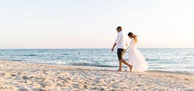The image depicts a couple walking along a beach