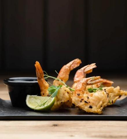 The image shows a gourmet dish of tempura-fried shrimp