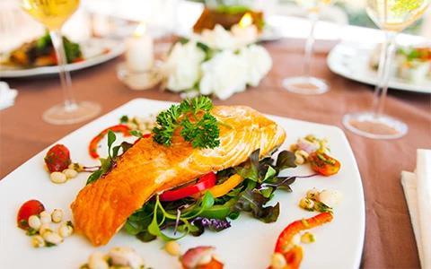 This image features a beautifully presented dish consisting of salmon on a bed of mixed greens, possibly including spinach, red and yellow bell peppers, and other salad ingredients