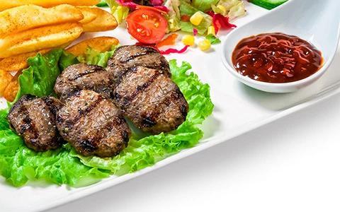 This image shows a plate of food containing grilled meat patties served on lettuce leaves, accompanied by a side of French fries and a colorful mixed salad that includes lettuce, corn, and cherry tomatoes