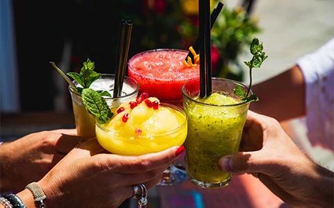 The image features four people holding colorful cocktails