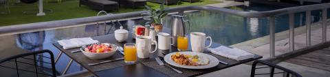 This image features an outdoor breakfast setting by a pool