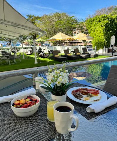 The image displays an inviting outdoor breakfast setup by a pool