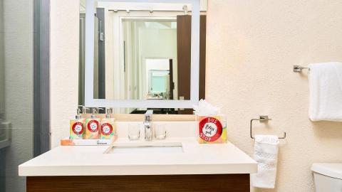 The image shows a bathroom vanity setup featuring a large rectangular mirror that reflects part of the bathroom and another mirror in the distance