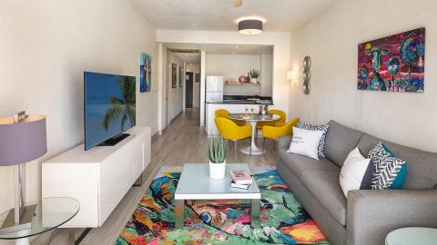 This image shows a modern living room that opens up to a kitchen area