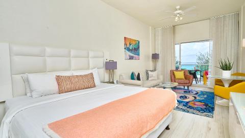 The image shows a stylishly decorated bedroom with a beachfront view
