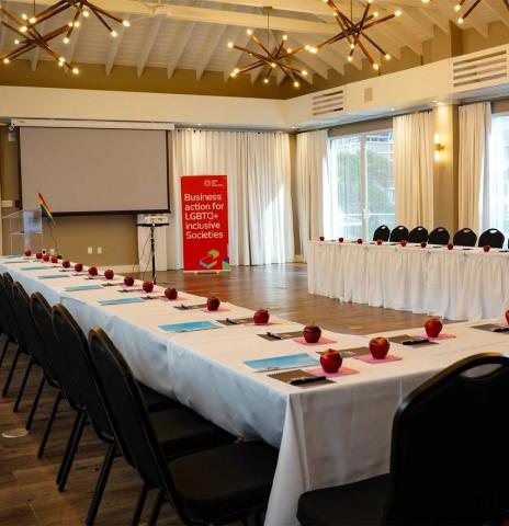 This image shows a conference room setting prepared for a formal meeting or event, with a focus on LGBTQ+ inclusion