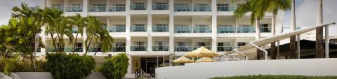 This image shows a modern, multi-story resort or hotel building featuring large balconies and white exteriors