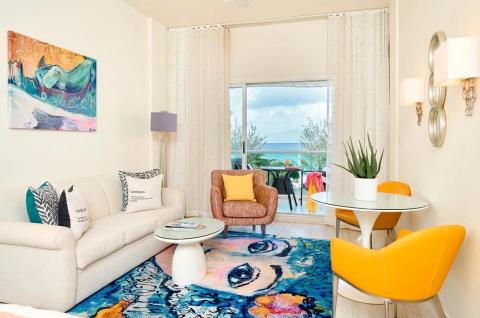 The image shows a stylishly decorated living room with a vibrant, beachy atmosphere