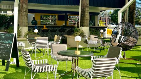 This image depicts an outdoor bar and seating area in a tropical setting