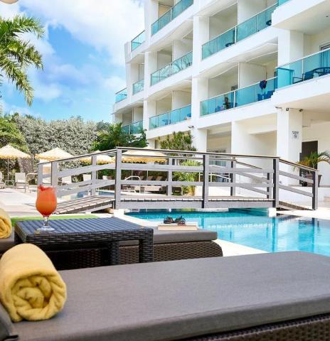 The image shows a luxurious outdoor pool area of a modern apartment or hotel complex