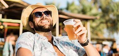 The image shows a man enjoying himself outdoors at what appears to be a festival or outdoor venue