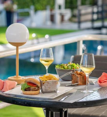 This image depicts an outdoor dining setup beside a swimming pool