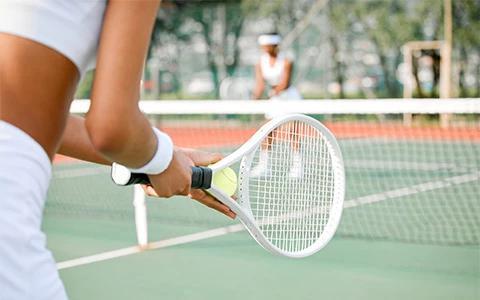 The image shows a close-up of a person holding a tennis racket, ready to play