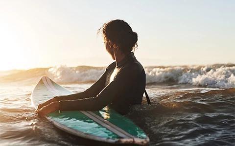 This image shows a person sitting on a surfboard in the ocean